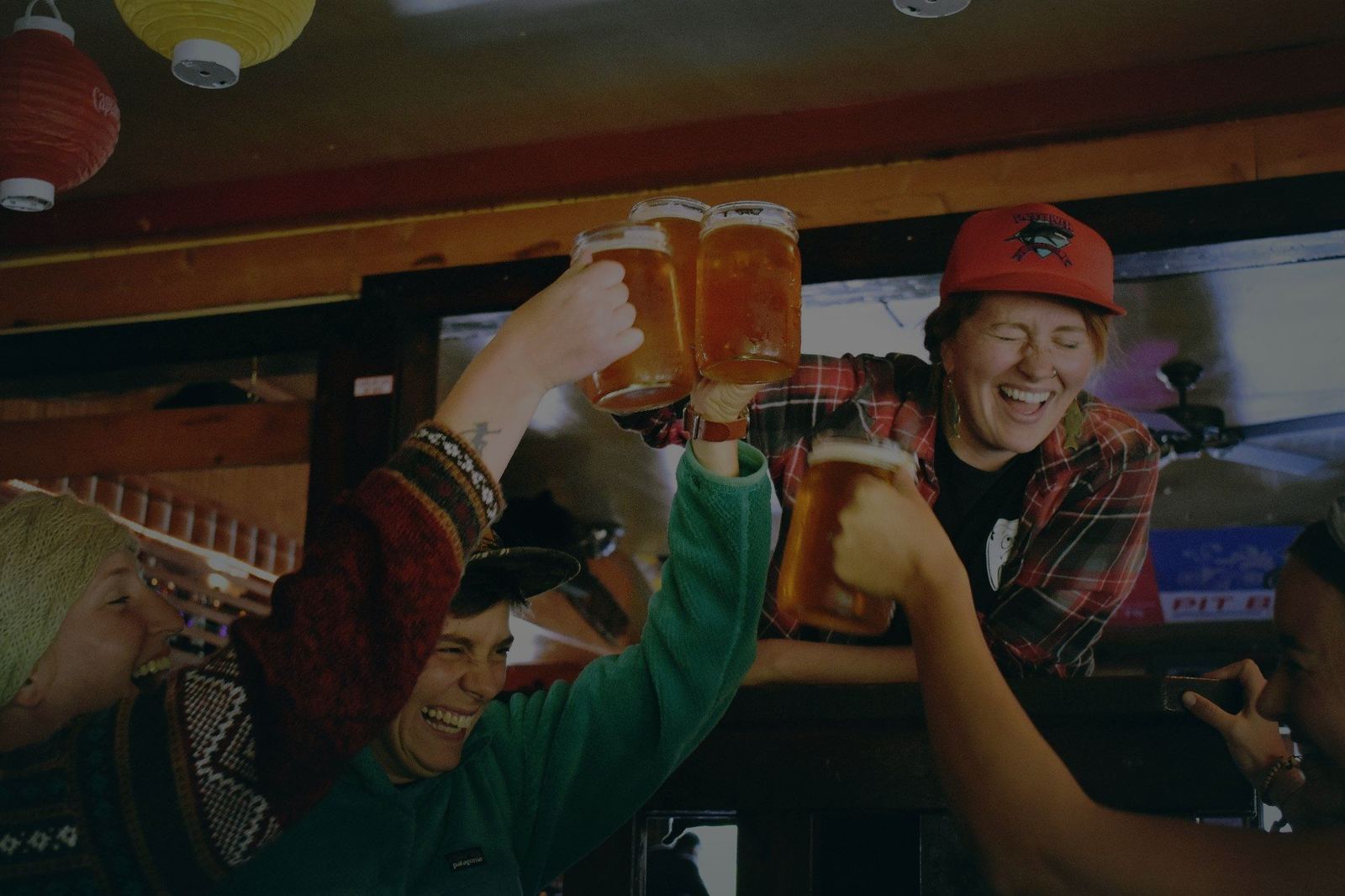 Friends raising freshly poured beers at a busy bar
